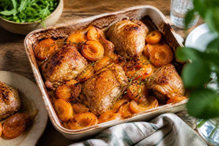 Aprikosen-Hähnchen aus dem Ofen auf einem Backblech mit goldener Glasur, frischen Aprikosen und Kräutern, Jamie-Oliver-Stil