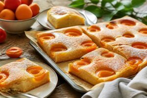 Saftiger Aprikosenkuchen vom Blech mit frischen Aprikosen auf goldenem Rührteig, frisch aus dem Ofen