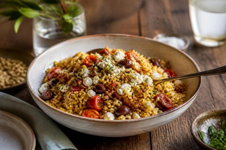 Knuspriger Ofenreissalat nach Hans Gerlach – gerösteter Jasminreis auf einem Kräutersalat mit cremiger Currysauce und Spiegelei, von oben fotografiert auf einem hellen Holztisch