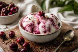 Vanille-Kirsch-Eis ohne Eismaschine in einer weißen Schale, mit frischen Kirschen und Vanilleschote garniert